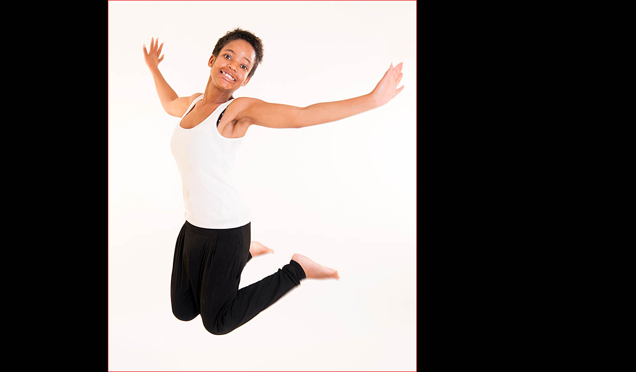 Simbi waring white top and black jeans jumping
